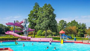 A swimming pool with multiple slides and a playground area.