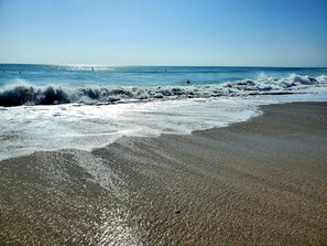 Een strand met golven en heldere lucht.