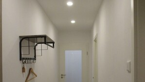 A narrow hallway with a wooden bench, a clothes rack, and a door at the end. - Vacation apartment in the heart of Saxony (Leisnig)