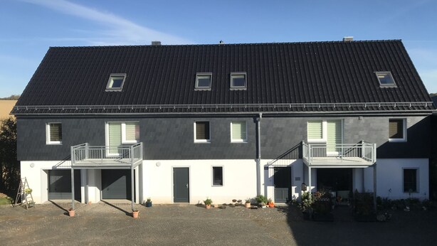 A two-story building with a dark roof, multiple windows, and balconies. - Vacation apartment in the heart of Saxony (Leisnig)