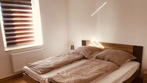 A single bed with a wooden headboard and a window with blinds. - Vacation apartment in the heart of Saxony (Leisnig)