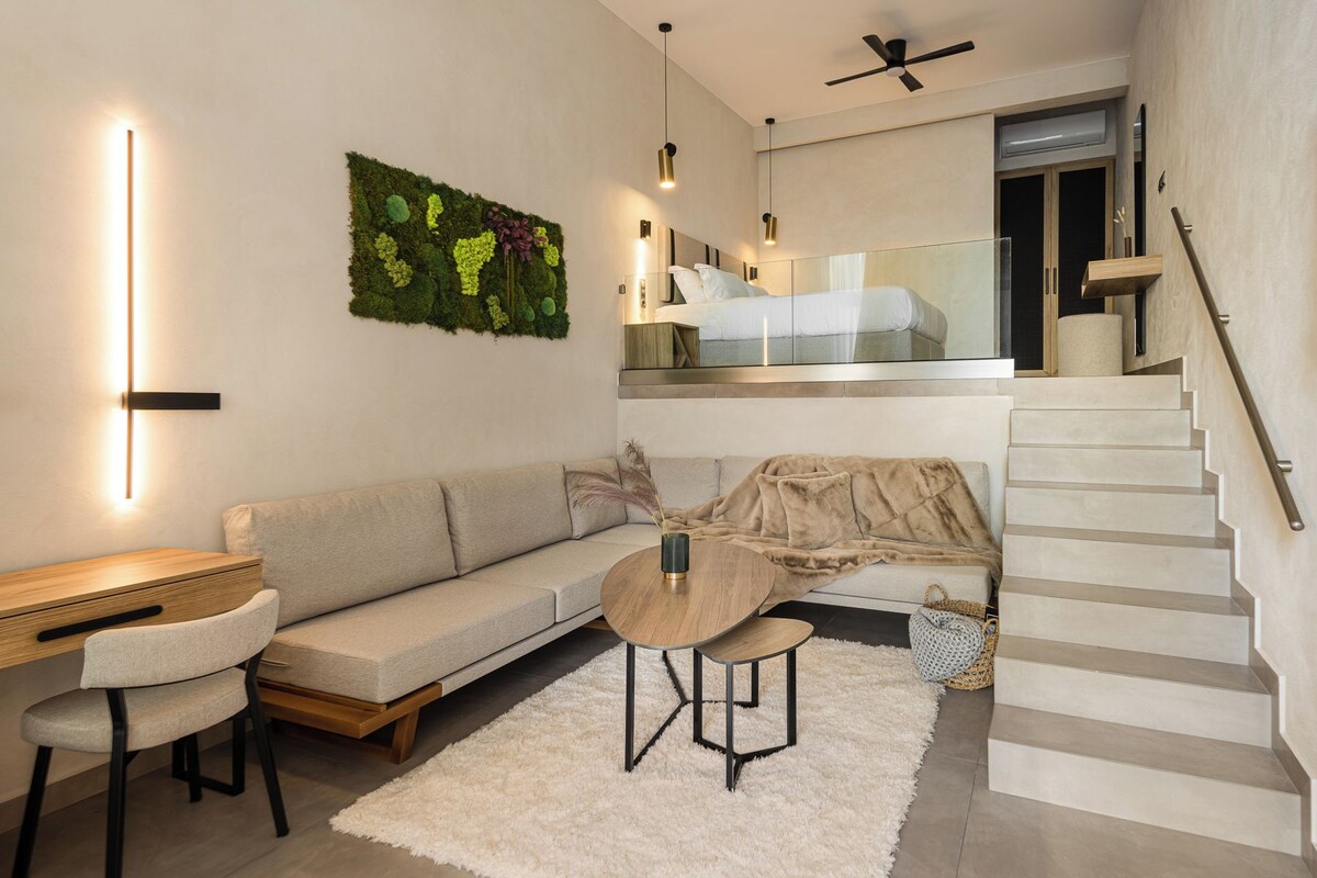 A modern living room with a sofa, a coffee table, a desk, and a staircase.