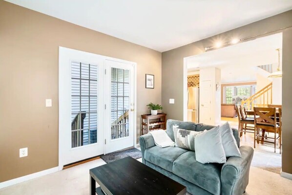A living room with a grey sofa, a black coffee table, and a door leading to a staircase.