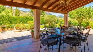 An outdoor patio with a table set for dining, surrounded by chairs, and a pergola overhead. - SON SEGUÍ - Villa with private pool in Alaró with free WiFi (Alaro)