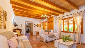 A cozy living room with a wooden ceiling, a sofa, a coffee table, and a window with curtains. - SON SEGUÍ - Villa with private pool in Alaró with free WiFi (Alaro)