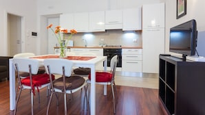 A modern kitchen with white cabinets, a dining area with red chairs, and a TV on a stand. - Apt next the Vatican both museum entrance\St Peter's basilica, Metro, a.c., wifi (Roma)