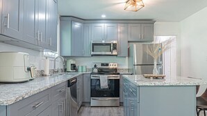 A modern kitchen with grey cabinets, stainless steel appliances, and a granite countertop. - Modern 3BR Family Home, Fenced Yard, Pets Friendly + 15 min to Stone Mountain (Snellville)