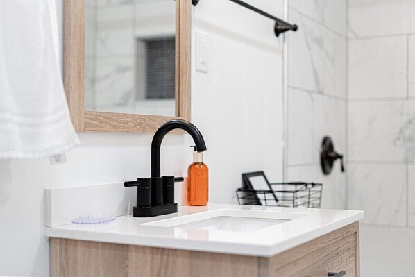 Une salle de bain moderne avec un lavabo blanc, un robinet noir et un meuble en bois.