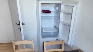 Un tavolo da pranzo in legno con quattro sottopiatti neri, due sedie e un frigorifero sullo sfondo.