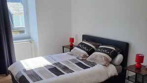 Una camera da letto con un letto, due comodini, una finestra e un lampadario.