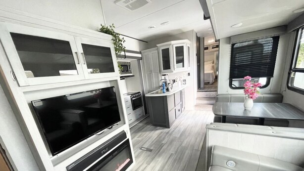A compact RV interior with a kitchenette, a seating area, and a TV. - Johnny Love, Modern and Bright Paradise RV (San Diego)