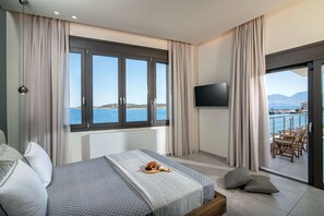 Un dormitorio con cama, televisor y balcón con vista al mar.