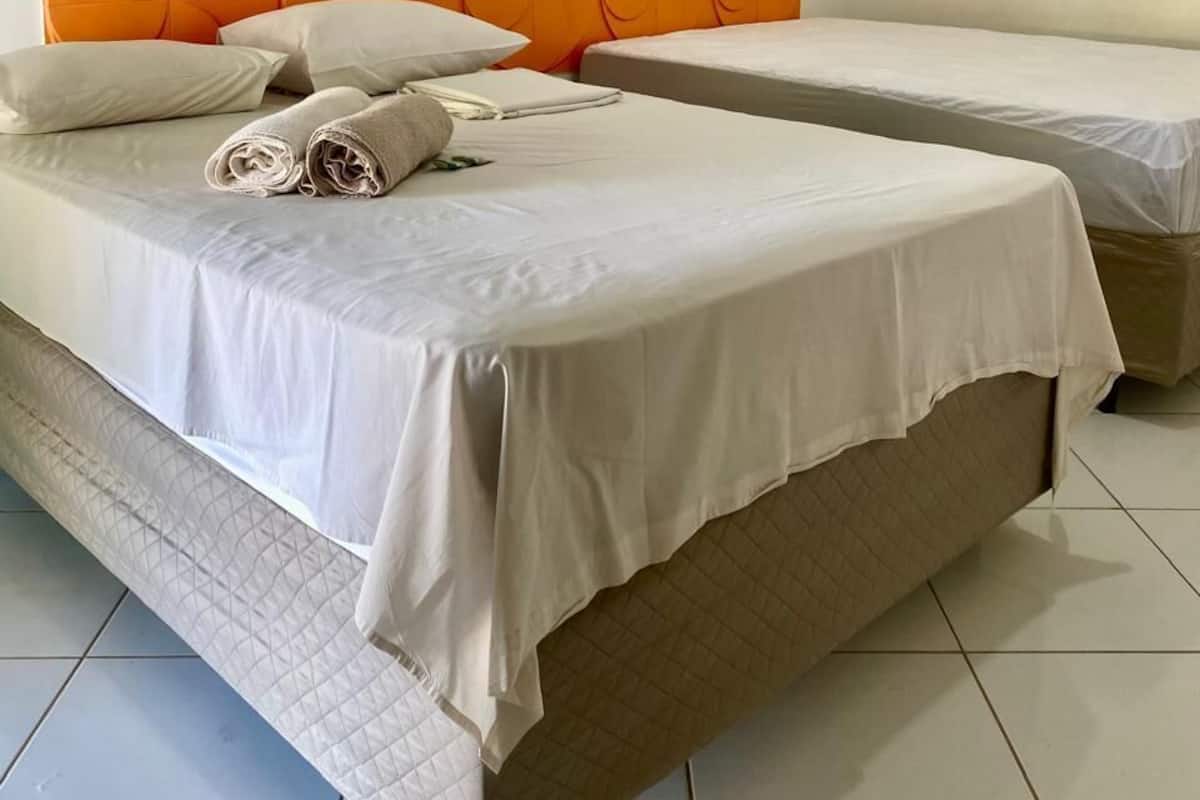A hotel room with two beds, a white headboard, and a tiled floor.