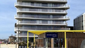 A multi-story building with a covered entrance and a bench in front. - Worthing Beach 180 - 2 bed Seafront With Parking (Worthing)