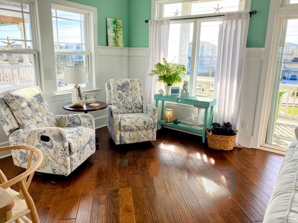 A living room with two patterned armchairs, a small round table, a potted plant, and a wicker basket. - SeaPrize! Elevator Beach Home, Ocean & Sound Views from 6 Decks, NTB, EV Charger (North Topsail Beach)
