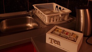 A kitchen with a sink, a stainless steel kettle, a white dish rack, and a box labeled "Tea". - Beautiful 1-bed Apartment in Sveta Nedelja (Sveta Nedelja)