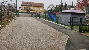 A playground with a slide and climbing structures, a covered seating area, and a gravel path leading to a building with a red roof. - Beautiful 1-bed Apartment in Sveta Nedelja (Sveta Nedelja)