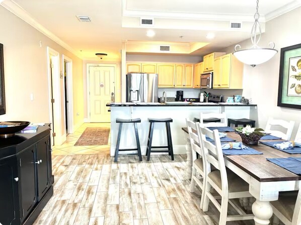 A modern kitchen with a central island, bar stools, and a dining table with chairs.
