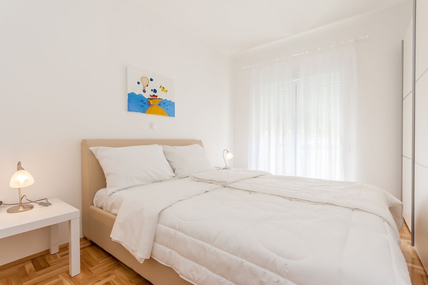 A minimalist bedroom with a bed, two bedside tables, and a wall-mounted artwork.