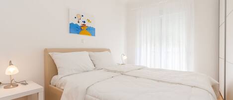 A minimalist bedroom with a bed, two bedside tables, and a wall-mounted artwork.