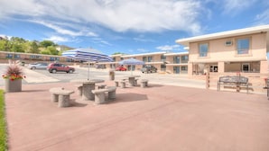 A hotel with outdoor seating, a parking lot, and a clear sky.