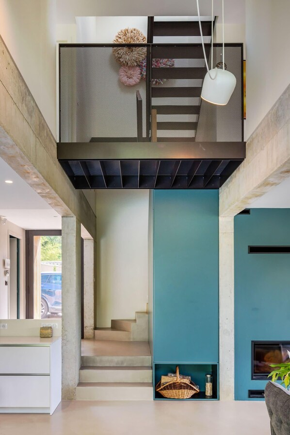 Un intérieur moderne avec un escalier, un luminaire suspendu et un panier au niveau inférieur.