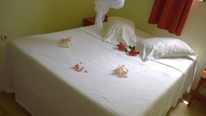 A neatly made bed with white linens and floral decorations.
