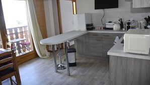 A kitchen with a bar stool, a refrigerator, a microwave, and a sink.