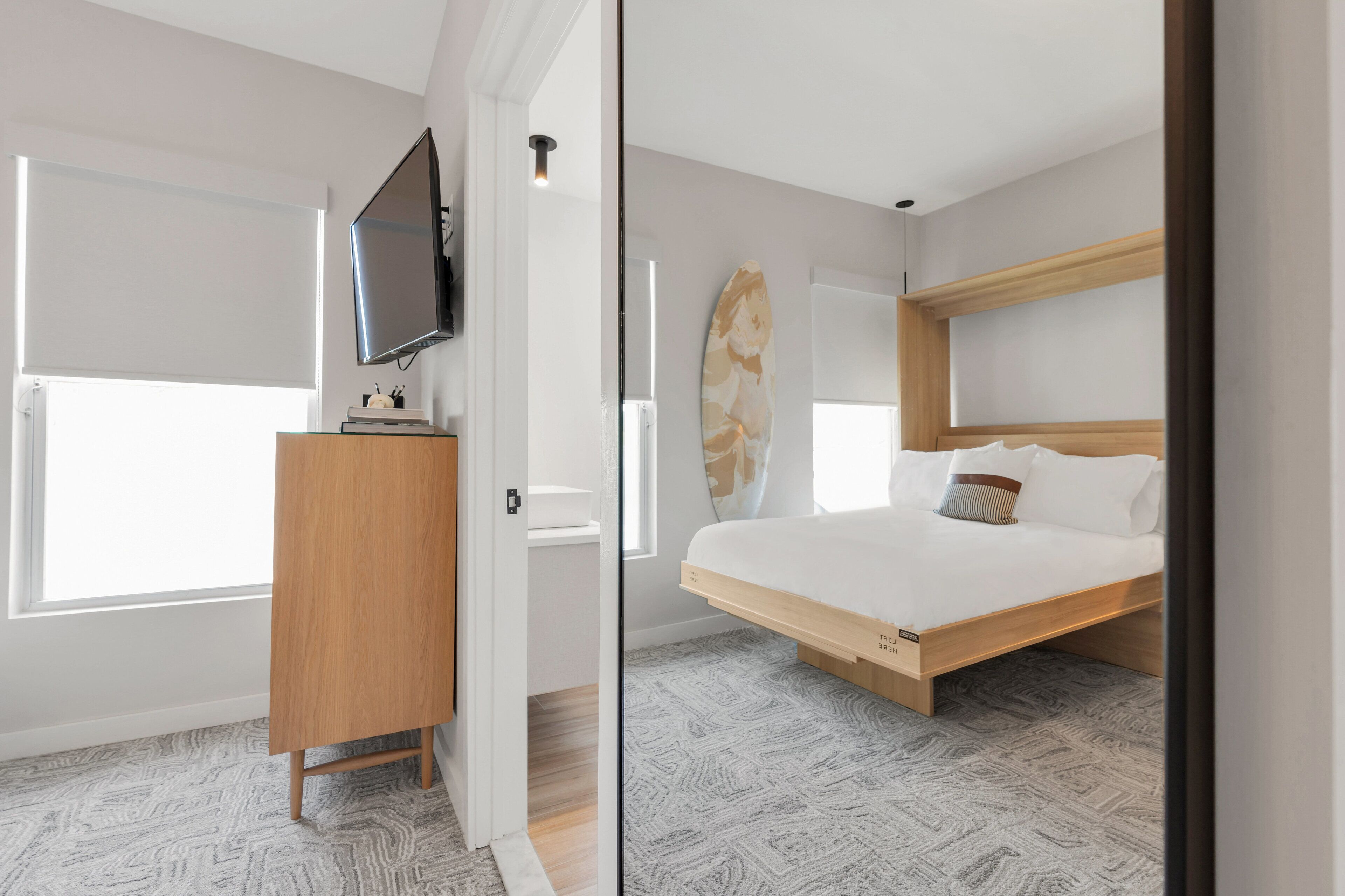 Une chambre à coucher moderne avec un lit, un téléviseur et une planche de surf.