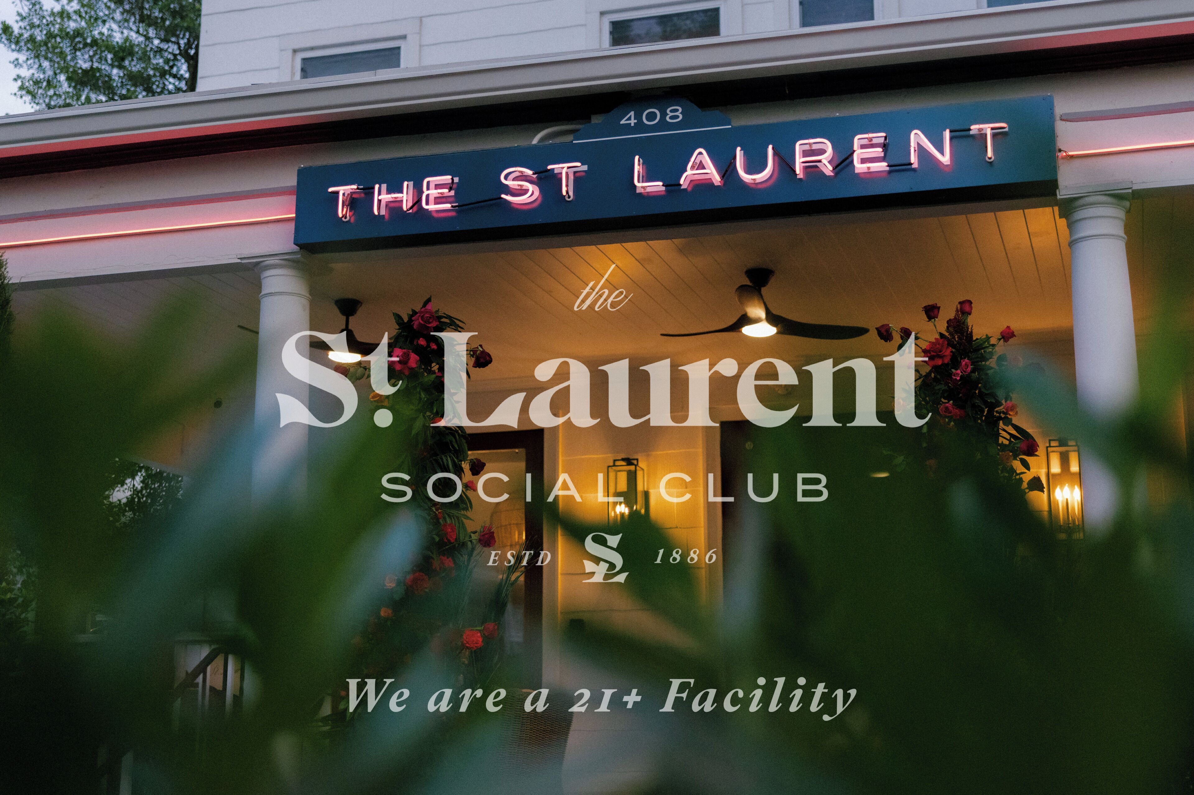 A sign for 'The St Laurent Social Club' with a neon sign, a columned entrance, and a floral decoration.