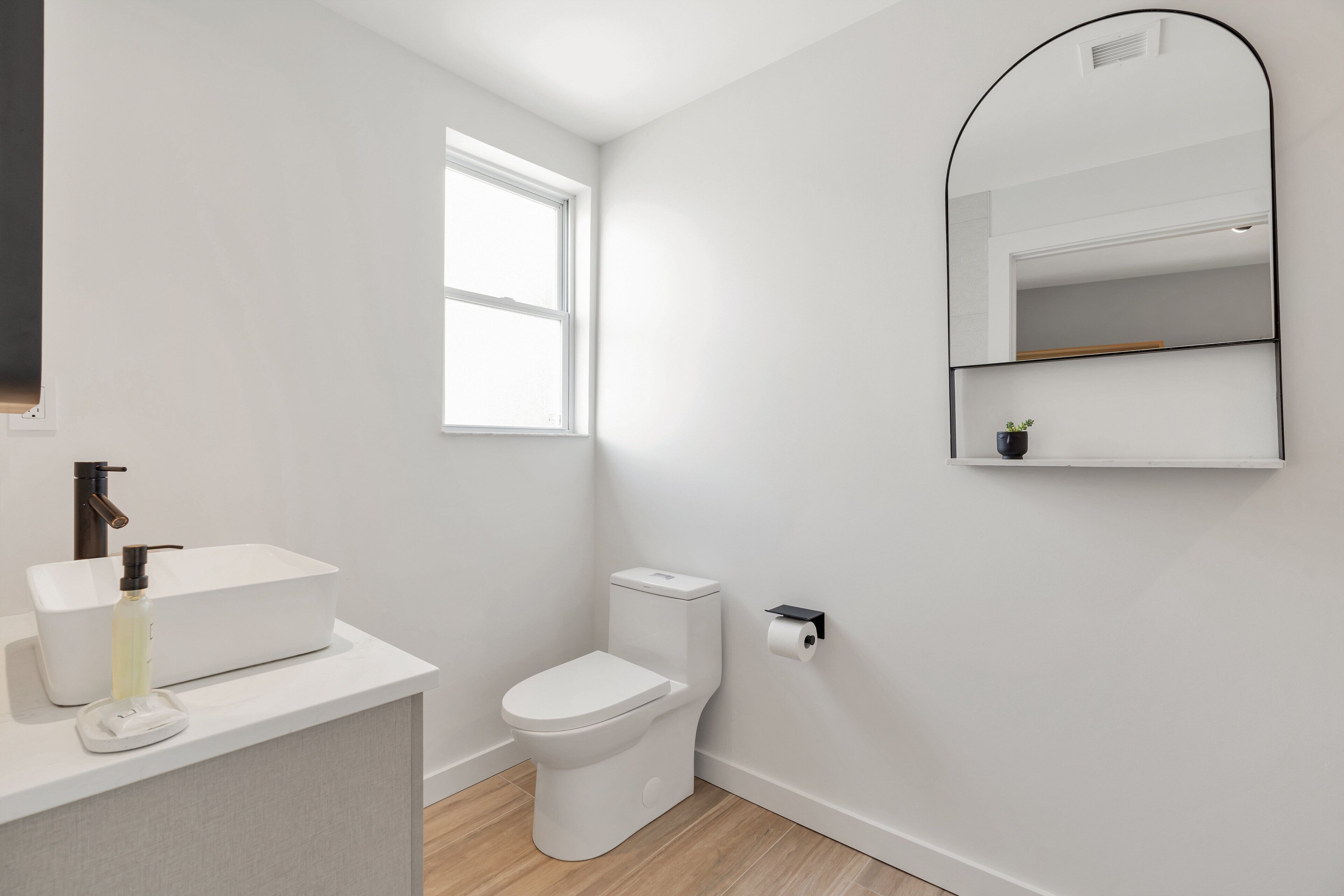 A modern bathroom with a white sink, toilet, and mirror.