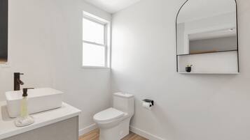 A modern bathroom with a white sink, toilet, and mirror.