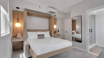 Un dormitorio moderno con estructura de cama de madera, un espejo grande y lámparas colgantes.