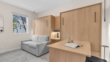 Ein modernes Zimmer mit einem grauen Sofa, einem Holztisch und einem Kleiderschrank.