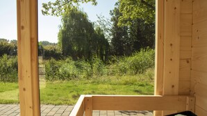 A wooden structure with a view of a grassy area and trees. - Dream cottage (Menslage)