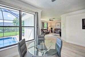 Ein modernes Wohnzimmer mit Glastisch, Ledersesseln, einer Couch und einem Deckenventilator.