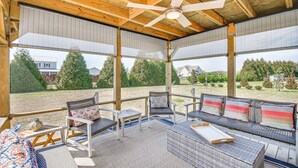 Un espace extérieur aménagé avec des meubles en osier, un ventilateur de plafond et une vue sur un quartier résidentiel.