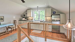 A modern kitchen with white cabinets, a stainless steel refrigerator, and a large window. - Barn-Like Studio Suite w/ Flowering Garden! (Titusville)
