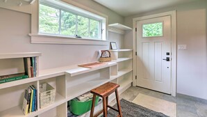 A room with white built-in shelves, a window, a door, and a small wooden stool. - Barn-Like Studio Suite w/ Flowering Garden! (Titusville)