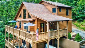 A two-story wooden cabin with a deck, hot tub, and outdoor seating area. - Spacious Murphy Chalet w/ Hot Tub: Mtn Views! (Murphy)