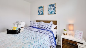 A neatly made bed with a patterned blue and white bedspread, a bedside table with a lamp, and a welcome sign. - ~ 4 Mi to Downtown Philadelphia: Cozy Retreat (Philadelphia)
