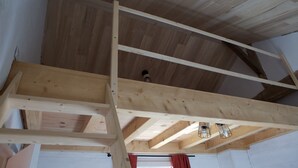 Een hoge plafond met zichtbare houten balken en een ventilatiekanaal.