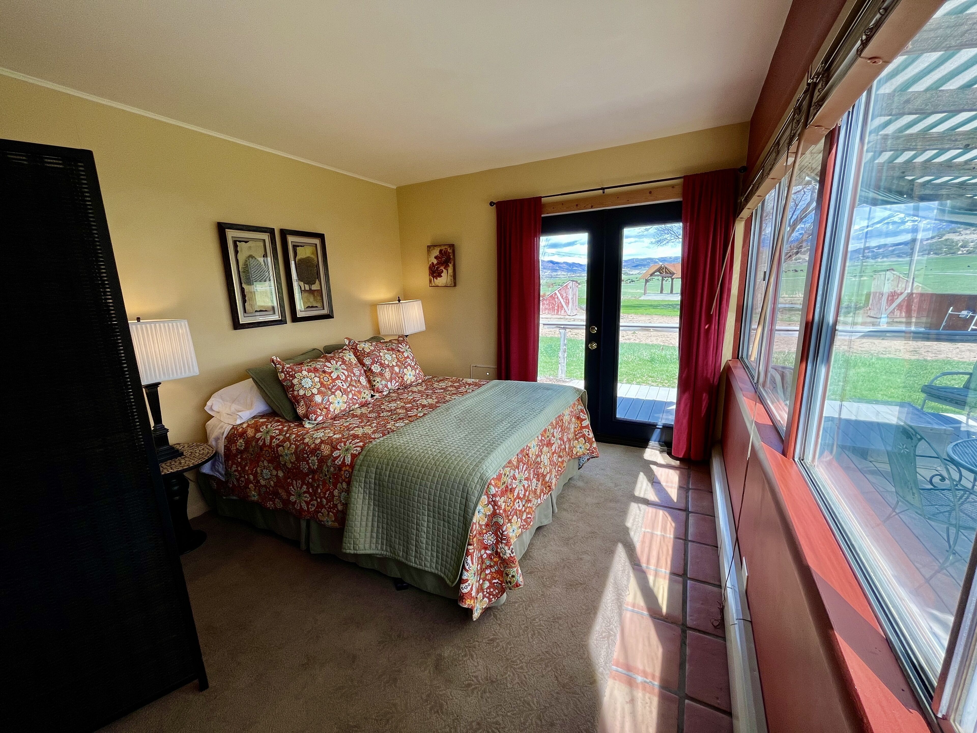 A bedroom with a bed, a lamp, a desk, and a window with curtains.