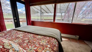 Une chambre avec un grand lit, une fenêtre donnant sur un jardin et un mur rouge.