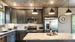 Une cuisine moderne avec des meubles de couleur sombre, des appareils en acier inoxydable et un îlot central en marbre.