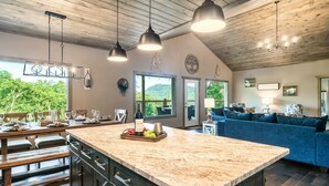 Une cuisine spacieuse avec un grand îlot central, un plafond en bois et des luminaires suspendus.