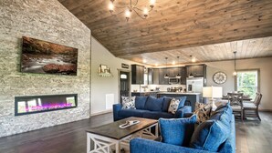 Un salon moderne avec un mur en pierre, une cheminée, un canapé bleu et un plafond en bois.