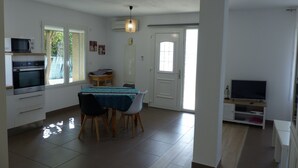 A compact kitchen with a dining area, a microwave, oven, and a TV. - Large air-conditioned T2, private parking near the center and beach (Banyuls-sur-Mer)