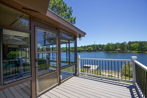 A wooden deck with a glass enclosure overlooking a lake. - Pinehurst Lake House - 4 Bedroom House with Pool! (Pinehurst)