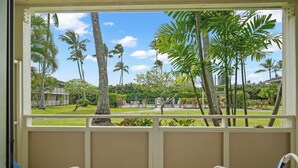 A room with a view of a tropical garden, two white chairs with blue cushions, and a small table. - Plantation Hale J2 | Relaxing Kapaa Escape on Kauai's Coconut Coast (Kapaa)